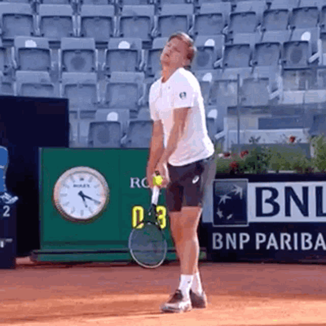 a man is holding a tennis racquet in front of a bnp pariba ad