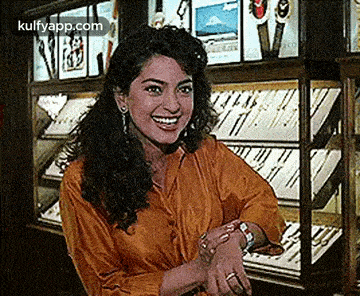 a woman is smiling while standing in front of a jewelry display case .