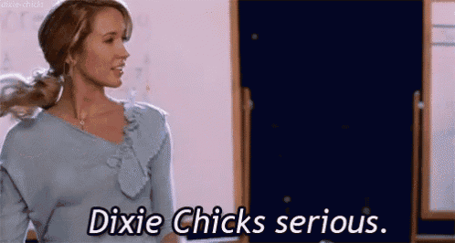 a woman in a blue shirt is standing in front of a blackboard and says dixie chicks serious .