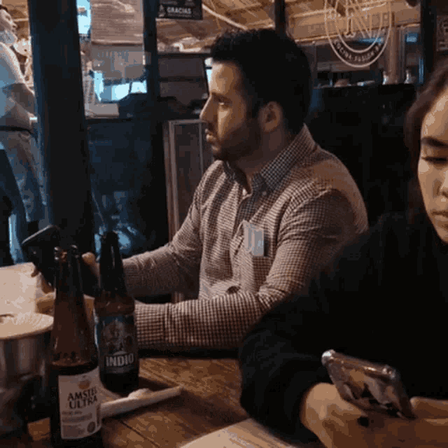 a man sitting at a table with a bottle of amstel ultra