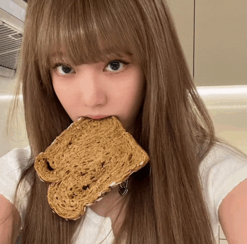 a woman is eating a slice of bread with a heart on it