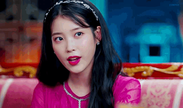 a close up of a woman wearing a headband and a pink shirt .