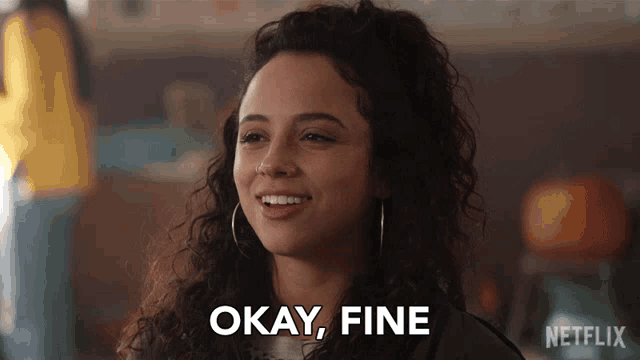 a woman with curly hair is smiling and says " okay fine "