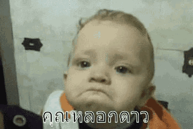 a baby is making a sad face with a foreign language written on it .