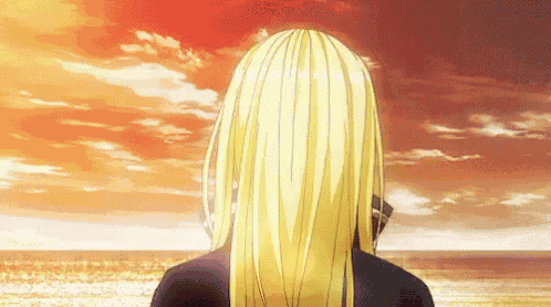 a woman with long blonde hair is standing on a beach looking at the ocean .