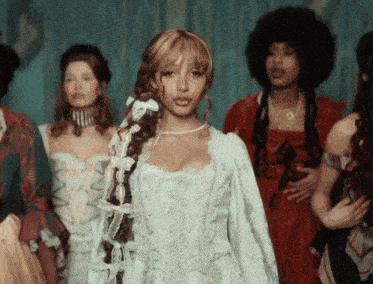 a woman in a white dress with a braid is surrounded by other women