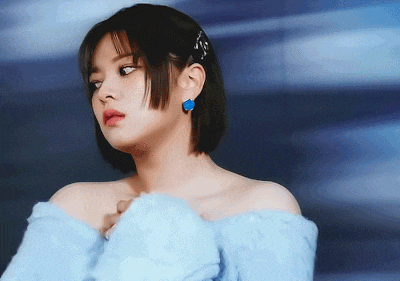 a woman wearing a blue off the shoulder top and earrings