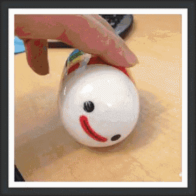 a person is holding a toy that looks like a snowman on a table