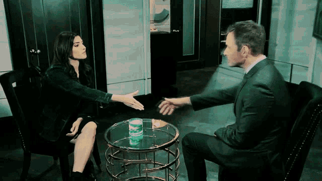 a man and a woman are sitting at a table talking to each other
