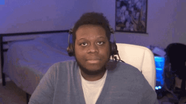 a man wearing headphones and a microphone is sitting in front of a bed