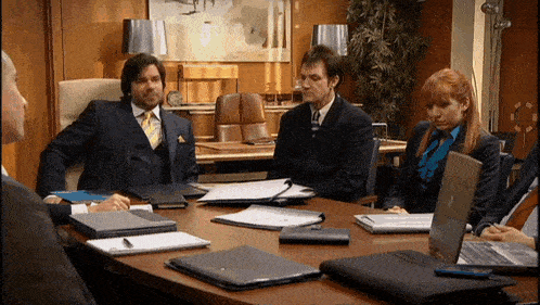 a man in a suit sits at a table with other people