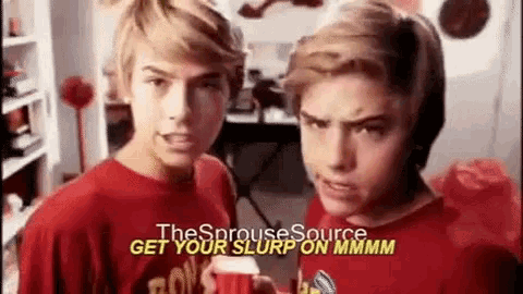two boys in red shirts are standing next to each other in a room and making funny faces .