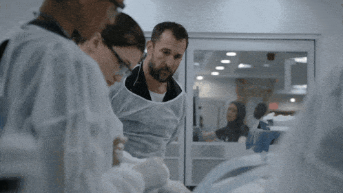 a group of doctors are looking at a patient in a room