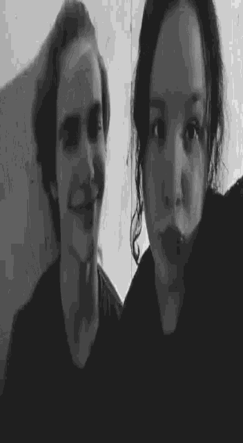 a black and white photo of a man and a woman giving a peace sign .
