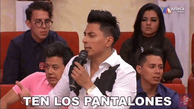 a man speaking into a microphone with the words ten los pantalones on the bottom