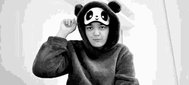 a black and white photo of a person wearing a panda costume and a panda mask .
