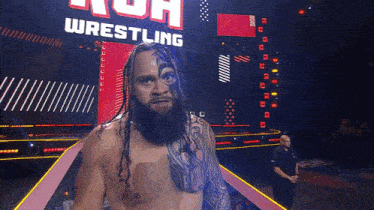 a man with dreadlocks stands in front of a wrestling sign