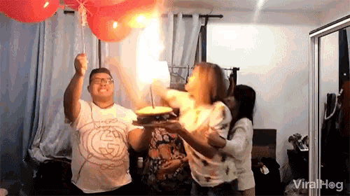 a man is blowing out a candle on a cake while a woman watches .