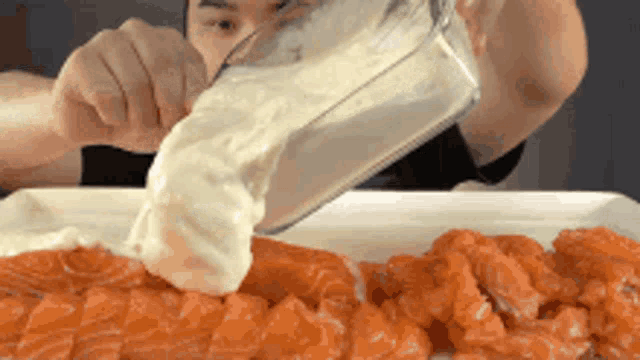 a person is pouring mayonnaise on a plate of salmon