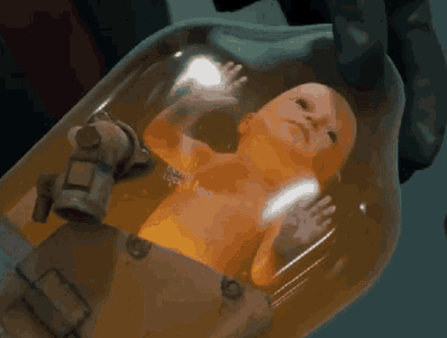 a person is holding a baby in a container that says ' i 'm a robot ' on the bottom