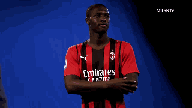 a soccer player wearing a red and black emirates jersey