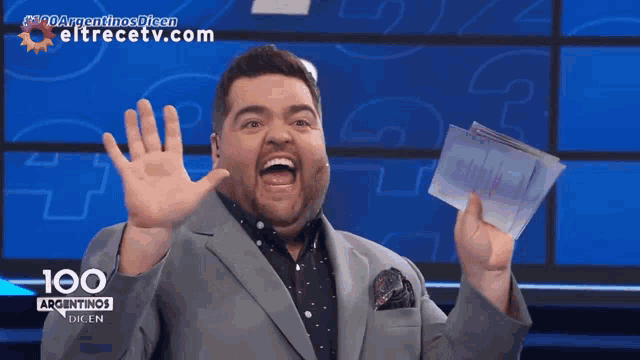 a man in a suit is holding a check in front of a screen that says hoo argentinas dien