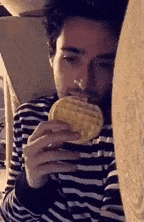 a man in a striped shirt is eating a waffle .