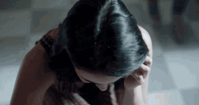 a close up of a woman covering her face with her hands .
