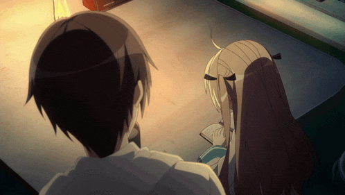 a boy and a girl are sitting at a table looking at something