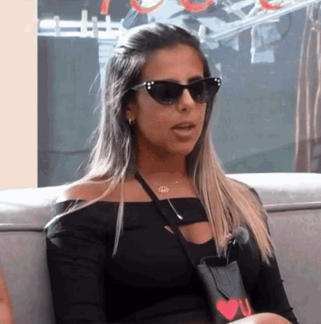 a woman wearing sunglasses is sitting on a couch