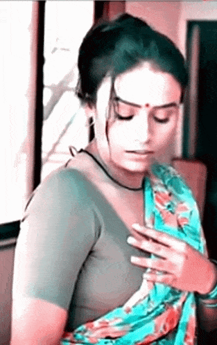 a woman in a floral saree is taking off her blouse .