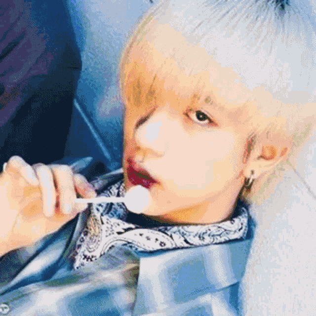 a close up of a person eating a lollipop with a bandana around their neck .