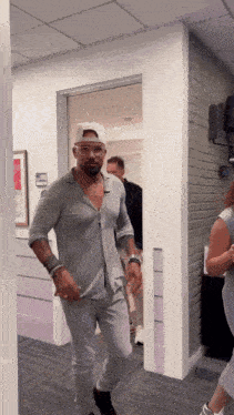 a man in a gray shirt and white hat is walking through a hallway
