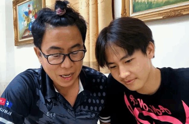 a man and a boy are looking at something together and the boy is wearing a shirt that says ' 018 ' on it