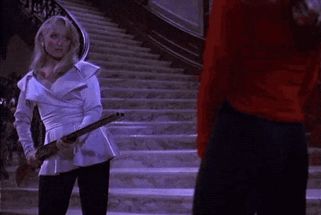 a woman is holding a sword while standing next to a man on stairs .