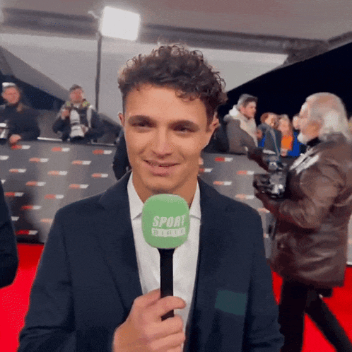 a man in a suit is holding a microphone that says sport