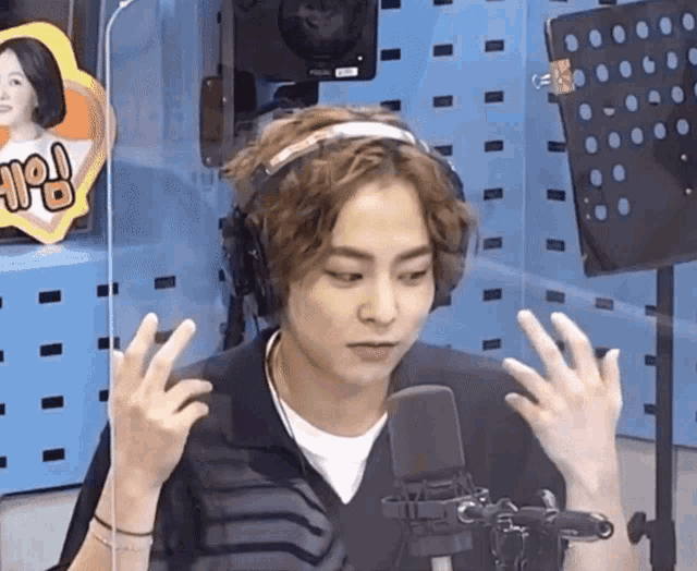 a man wearing headphones is standing in front of a microphone with his hands in the air