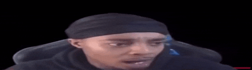 a man wearing a black headband is making a funny face while sitting in a chair .