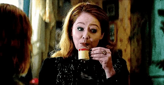 a woman is drinking a cup of coffee with a spoon .