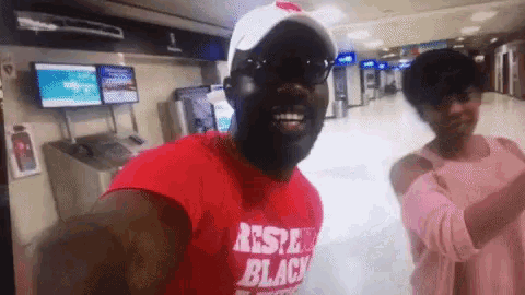 a man wearing a red shirt that says respect black is standing next to a woman