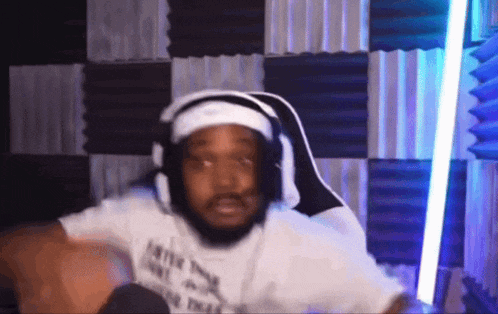 a man wearing headphones and a headband is sitting in a gaming chair .