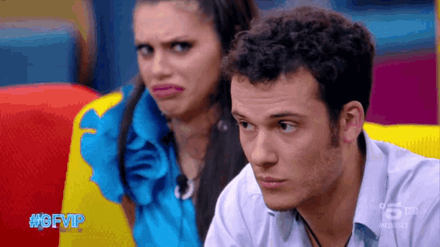a man and a woman are sitting on a colorful couch with #gfvip on the screen