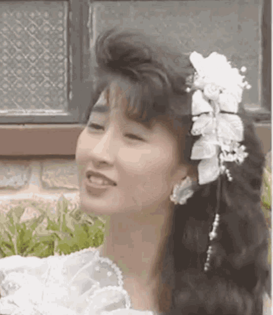 a woman in a white dress with flowers in her hair .