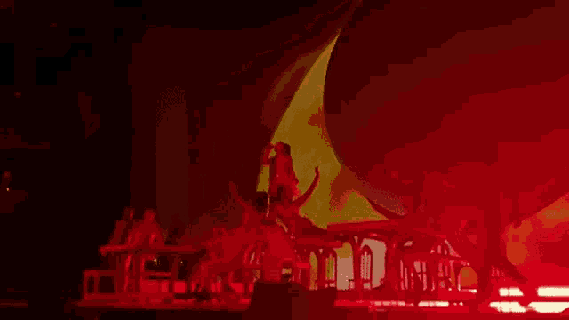 a group of dancers are performing on a stage in front of a large red balloon .