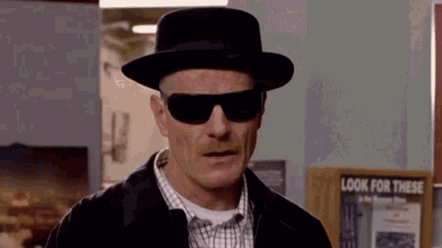 a man wearing sunglasses and a hat is standing in front of a sign that says look for these