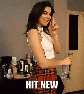 a woman wearing a plaid skirt and a white top is holding a bottle of water .