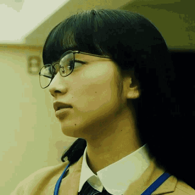 a close up of a woman wearing glasses and a blue lanyard