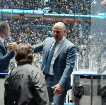 a man in a suit is shaking hands with a security guard in a stadium .