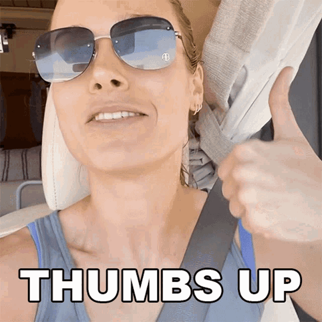 a woman wearing sunglasses giving a thumbs up