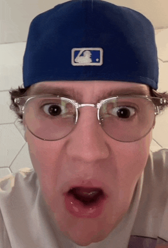 a man wearing glasses and a blue hat with a logo on it